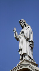 Fototapeta na wymiar Jesus Christ statue atop a church with blue sky in the background - Savior concept.