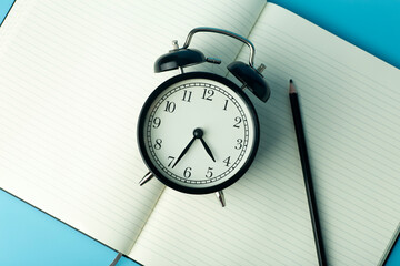 Notepad for sticky notes on desktop with alarm clock. Office desktop, management and timing concept.