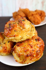 Closeup Pile of Tasty Garlic and Herb Biscuits with Blurry Fried Chickens in Background