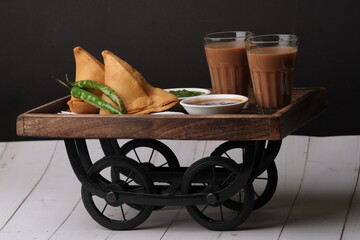 Indian snack Homemade spicy and delicious samosa served with green, tamarind chutney cutting masala tea, chai, 
