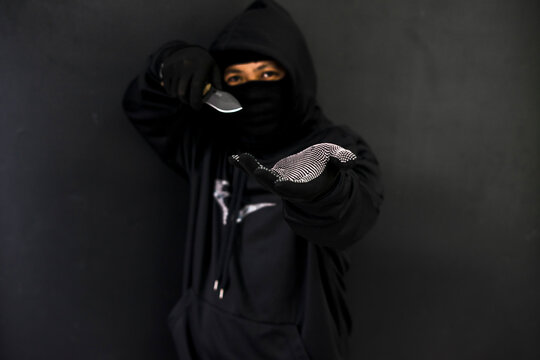 Dangerous man threatening with a knife in the dark street. Robbery concept. Focus on the knife.
