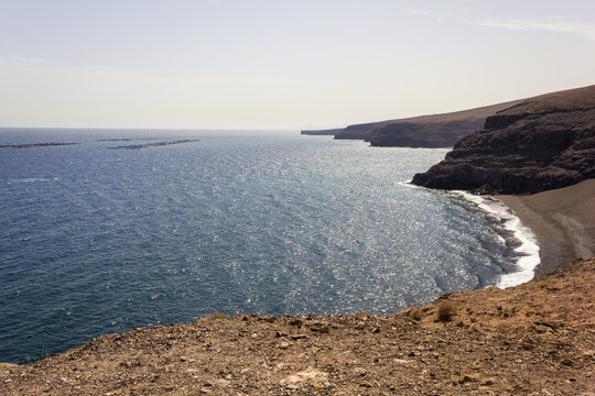 Lanzarote Volcanic Coast With Fish Farm Floating On Blue Ocean Offshore. Aquaculture Concept