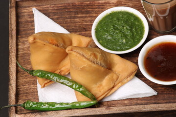 Indian snack Homemade spicy and delicious samosa served with green, tamarind chutney cutting masala...
