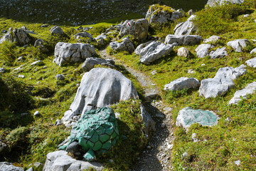 Naklejka na ściany i meble Giant turtle guarding tourists on the walking trail high in the mountains in Swiss Alps