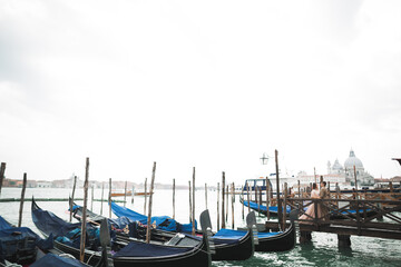 Fototapeta na wymiar Wedding couple staying on a bridge near the canal with gondolas in Venice, Italy
