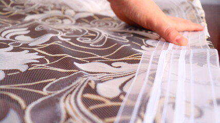 A female hand applies a tape to the curtains fabric, close-up.