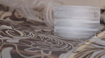 Tape and fabric for curtains close-up. Technological process of sewing curtains.