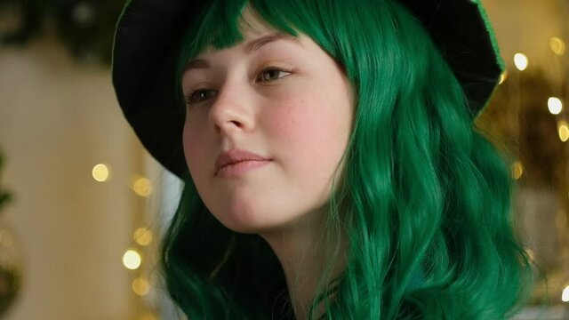 Beautiful teen girl with colored green hair and green hat smiling. Saint Patrick's day celebration concept, party time.