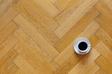 Coffee cup on a classic herringbone parquet floor with space for text - 407036382