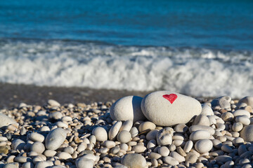 I love you and heart painted with a red paint marker on the pebble as a gift for Saint Valentine's day on the pebble background. Spontaneous symbol of love and passion. Copy space for text. 