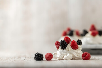 Homemade delicious Pavlova meringue cake with fresh raspberries and blackberries on a wooden background. Close-up. Copy space.