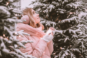 a young girl stands in the winter forest and looks up dreamily, holding a thermos in her hands woman in the forest