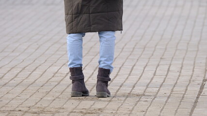 Obraz na płótnie Canvas Legs of a girl standing on the sidewalk