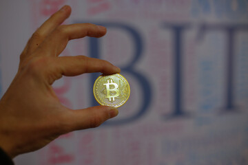 Man Holding Bitcoin In His Hand. Bitcoin Shows On Screen. Close Up shot