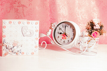 Vintage white clocks with the flowers biuqet abd the holiday card with flowers and heart on the rose background  are decorating a girl's room for Valentine's Day