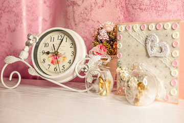 Christmas tree toys in the shape of an angels and the rose holiday card with flowers bouqet and vintage clocks are decorating a girl's room for Valentine's Day
