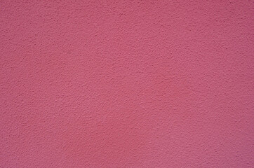 Fototapeta premium Pink decorative plaster on the facade of the building. Abstract rose decorative stucco wall texture. Rosy background with copy space for text. Beautifully stuccoed wall of house.