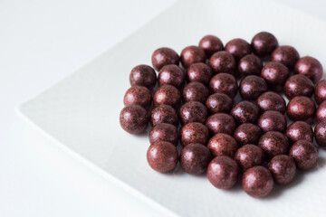 Handmade chocolate candy on white plate close-up. Tasty luxury dessert. Chocolatier sweet shop business concept