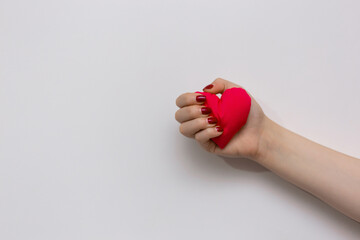 Red heart in the hand of a girl isolated on white background. Valentine's day Symbol. Red heart held tightly in hand representing pure love. Saves a life. Everything is in our hand.