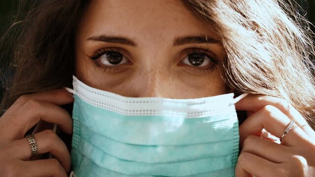 coronavirus - serious beautiful girl wears the mask looking at camera