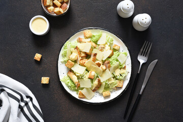 Fototapeta na wymiar Classic Caesar salad with chicken and sauce in a plate on a concrete background, top view.