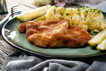 Pork chop served with mashed potatoes and pickled cucumber.