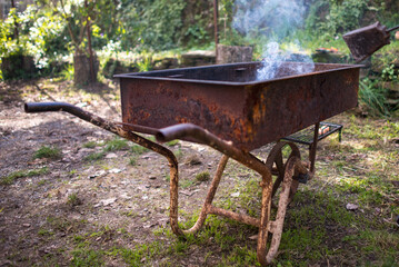 carretilla metálica oxidada con fuego en el interior en el campo