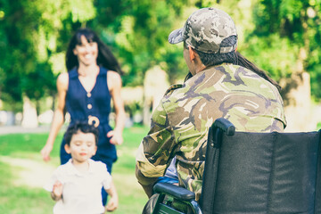Two happy kids and their mom running toward disabled retired military father and hugging him....