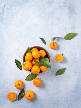 Flat lay sweet and juicy tangerines in a wooden bowl and a few tangerines on a blue background © Kufotos