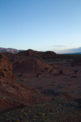 Fototapeta premium The red canyon and rocky valley at sunset. Panorama view of the arid desert, sandstone formations, and hills in Talampaya national park in La Rioja, Argentina.