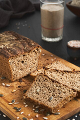 Leavened bread, whole grain rye bread with pumpkin and sunflower seeds. Leaven starter on table. Authentic sourdough homemade bread-organic bio product. Handcrafted product, slices of bread on board