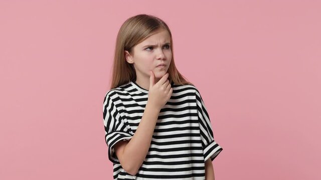 Confused puzzled little blonde kid girl 12-13 years old in striped casual t-shirt isolated on pastel pink color background studio. Childhood lifestyle concept. Put hand prop up on chin spreading hands