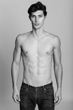 Studio shot of young handsome man standing shirtless