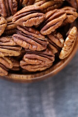 Pecan nut close-up in a round wooden cup on a black shabby  background.Nuts and seeds. .Healthy fats.Heap shelled Pecans nut closeup.keto diet.Tasty raw organic food snack