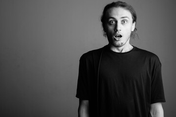 Fototapeta premium Young handsome man wearing black shirt against gray background