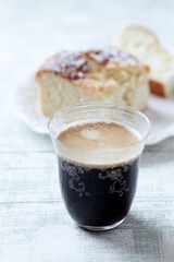 Coffee in glass cup on bright wooden background. Close up.