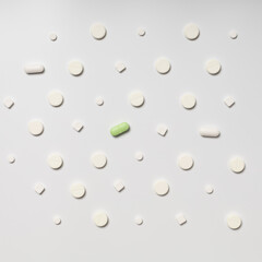 One colored pill on a background of white pills