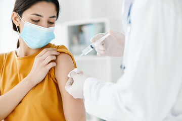 patient in a medical mask looks at the doctor with a syringe in hand vaccination