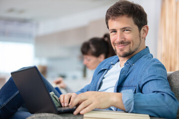 Obraz premium young attractive smiling guy is browsing on his laptop