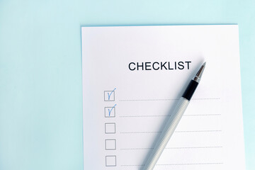 Close-up of on Checklist with pen on a blue background.