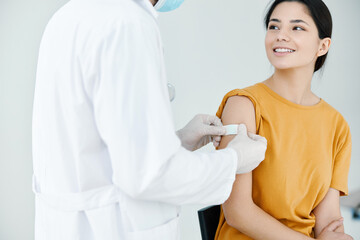 doctor in protective gloves tapes the shoulder of a woman 