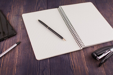 notebook with pen on wooden table with a phone