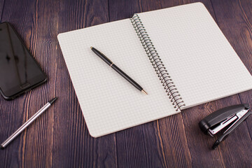 notebook with pen on wooden table with a phone