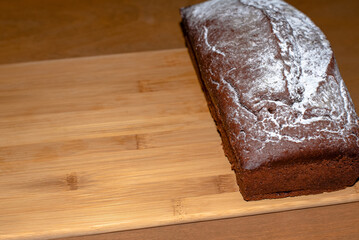 Chocolate loaf cake on a wooden cutting board. Freshly baked at home traditional bakery product.