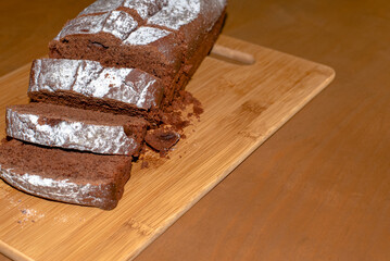 Chocolate loaf cake on a wooden cutting board, freshly baked at home and sliced