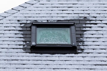 A portrait of a frozen slate roof with a skylight window which is also frozen during winter time....