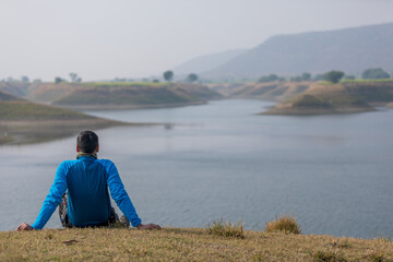 man sitting by lake