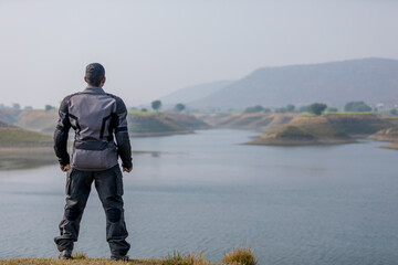 Naklejka premium biker standing by lake water