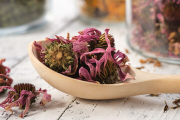 Wooden spoon of healthy echinacea petals and buds for making tea. Glass jars of dried coneflowers and medicinal herbs on background. Alternative medicine. - obrazy, fototapety, plakaty