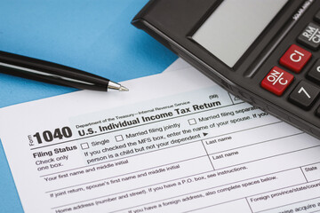 Close Up of Tax Form 1040 and Calculator on Light Blue Background
